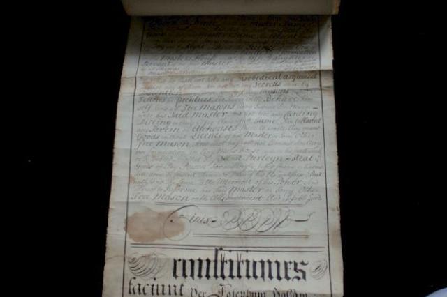 Unrolled pale parchment with black handwriting, laid on a black background