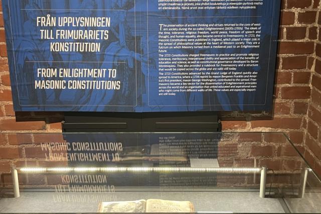 Gladd display case containing printed book from 1723, under a blue interpretation panel with white writing