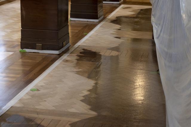 Partly sanded floor showing mahogany-paneled columns