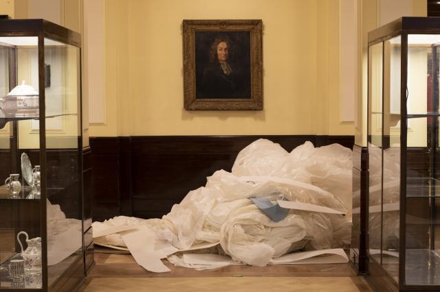 Portrait hanging above disguarded floor overing ready for disposal