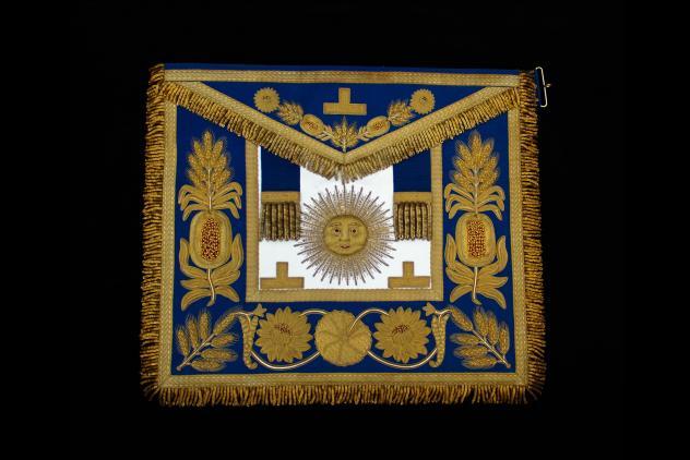 Gold and blue embroidered apron with a sun in the centre