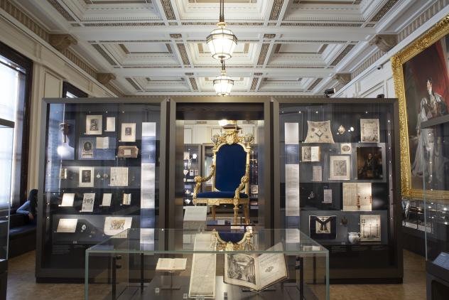 View of North Gallery showing large gold throne with blue cushions surrounded by glass display cases